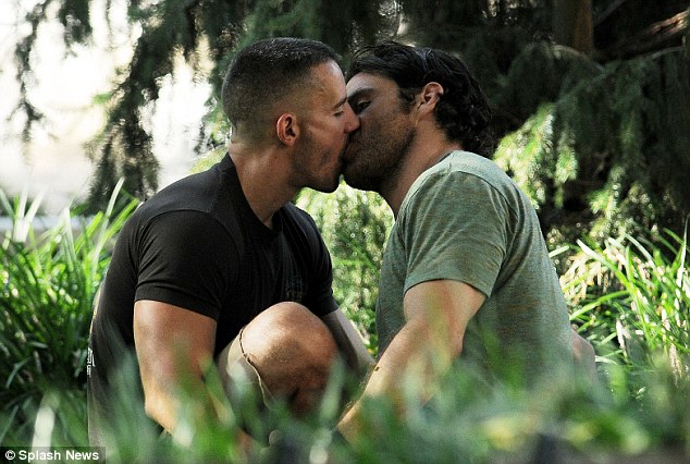 Ben Maisani black t shirt full on kiss with man in green shirt sitting in the park